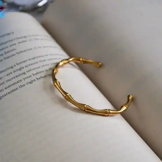 Gold bamboo bangle bracelet on open book pages