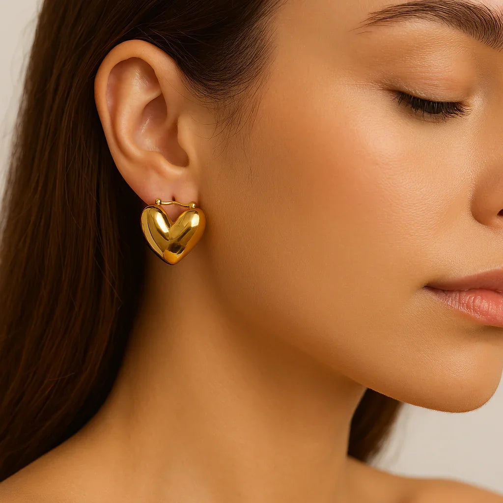 Woman wearing shiny gold heart shaped earring, close-up jewelry on ear